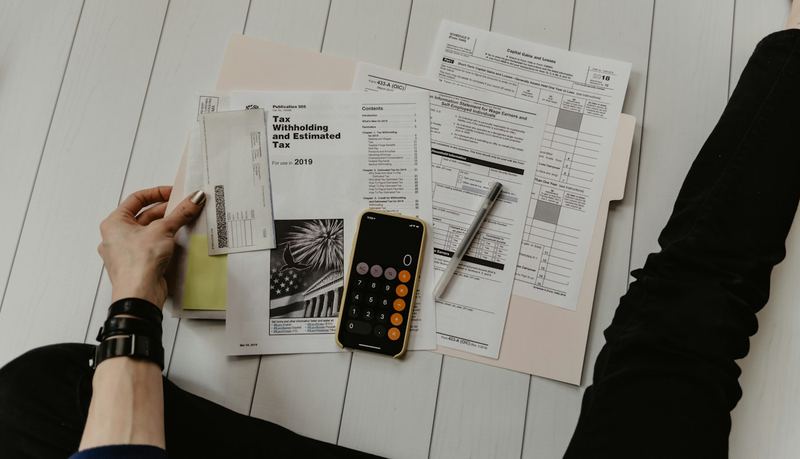 Documentos fiscais, celular e calculadora sobre uma mesa